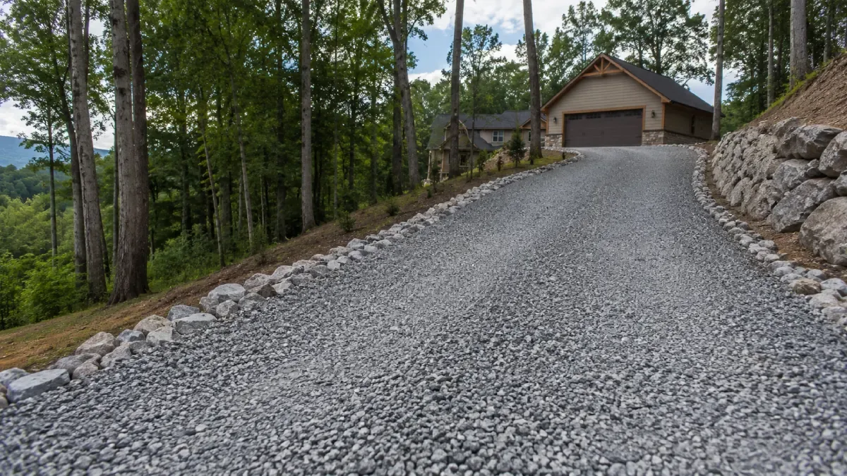 Fresh crushed-stone driveway running uphill through the trees to a detached garage